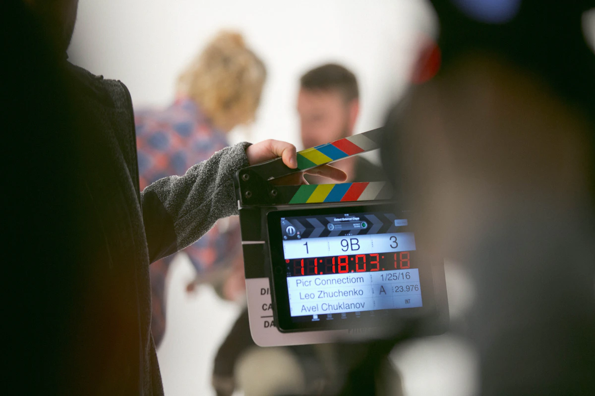 Une main tient un clap sur un plateau de tournage