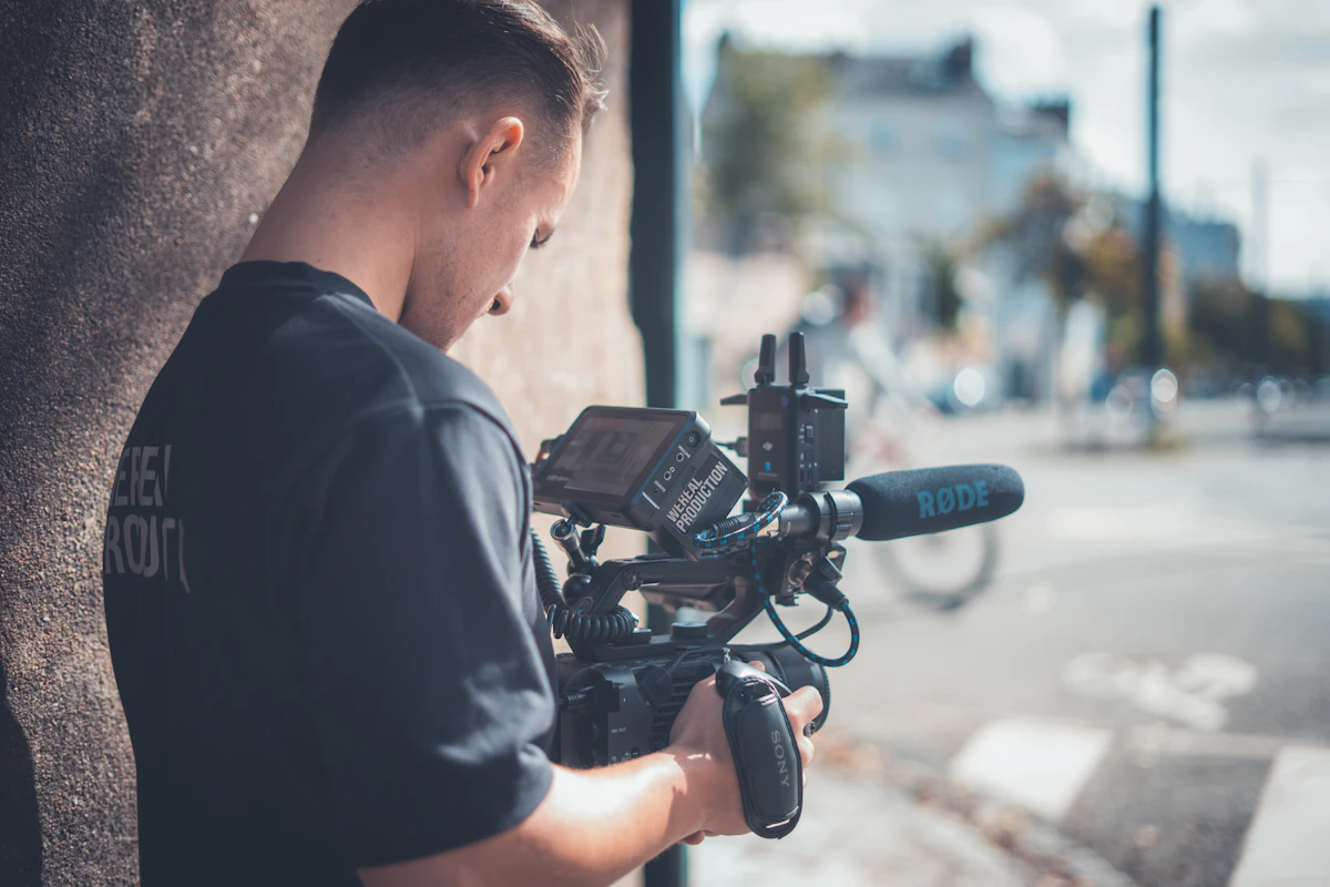Une personne tient une caméra équipée d’un microphone pendant un tournage